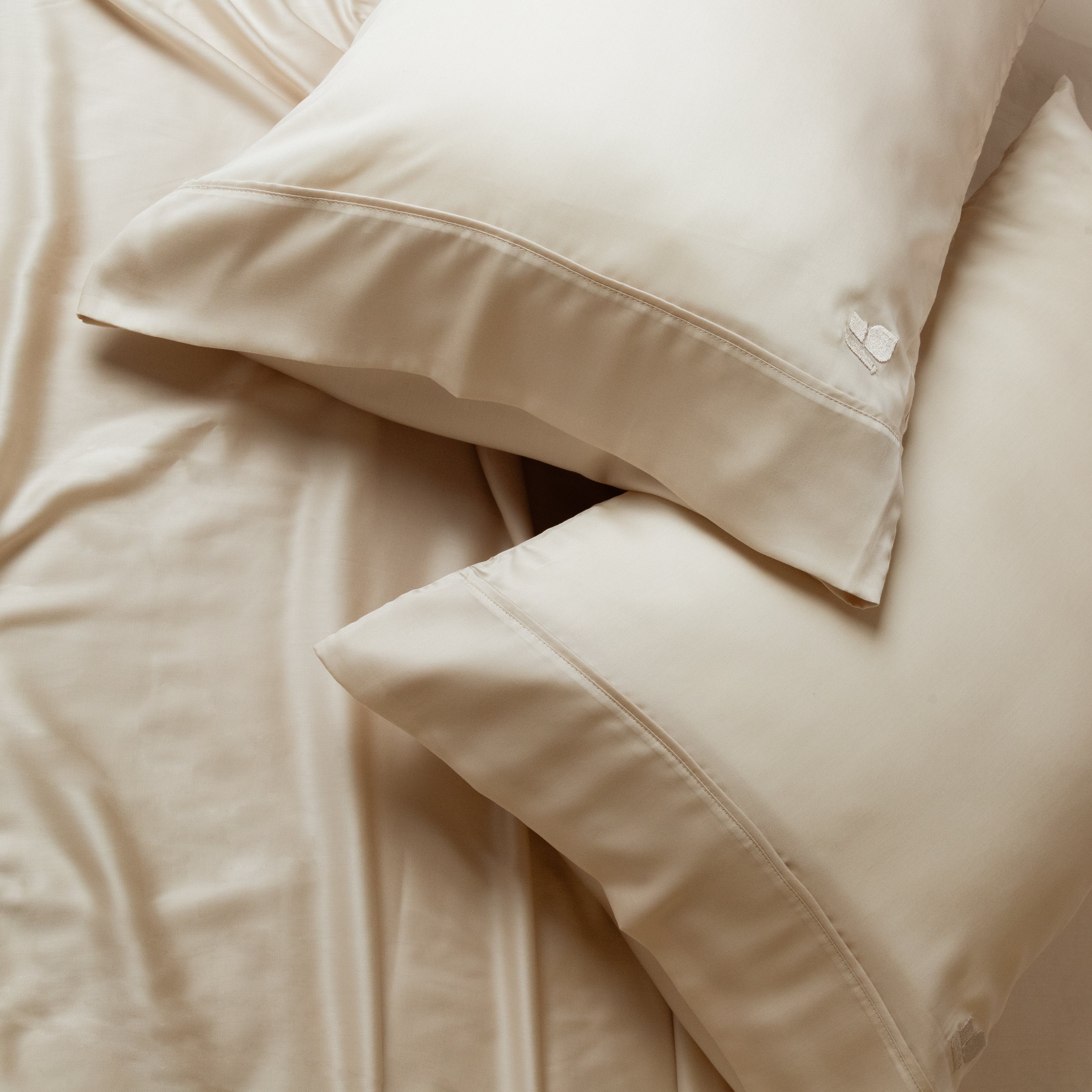 Eucalyptus TENCEL pillowcases and sheets in warm ivory, with the stitched hem and embroidered detail visible